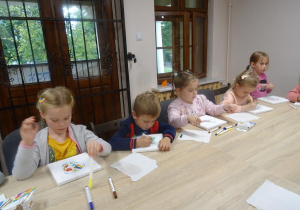 Pięcioro dzieci maluje na płótnie.